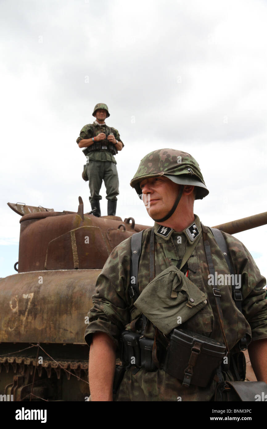 Tank commanders are watching over us. Two German WW2 soldiers, one standing on a tank with binoculars, the other on the ground. Stock Photo