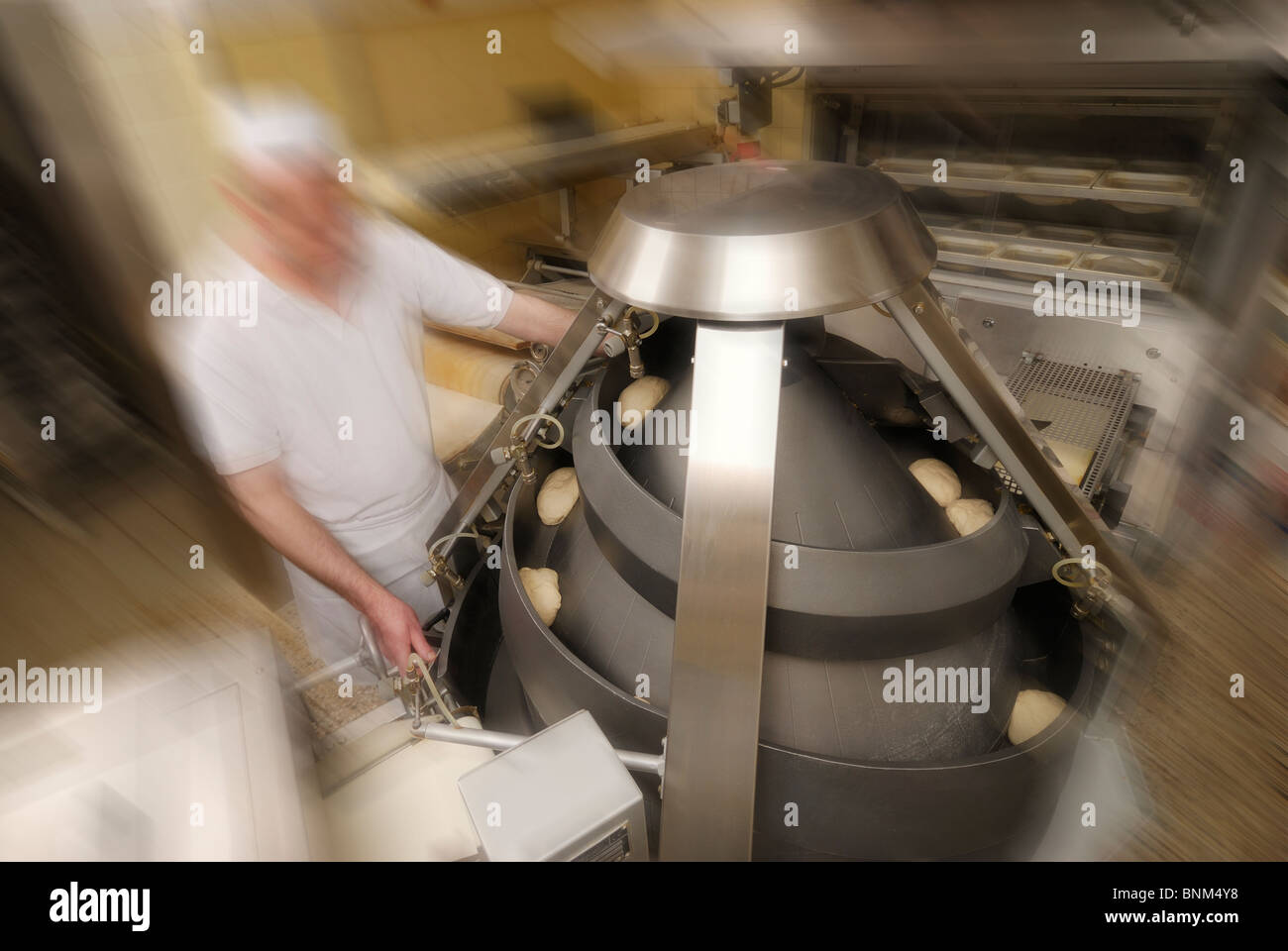 pastry process to bread, machine preparing pastry to bread blanks, blurred baker Stock Photo