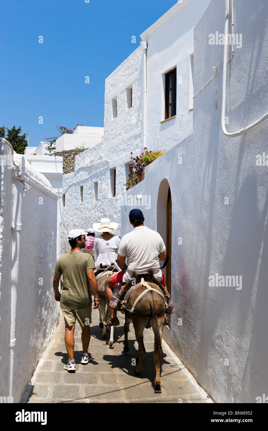 Tourists riding donkeys up to the Acropolis in the village of Lindos, Rhodes, Greece Stock Photo