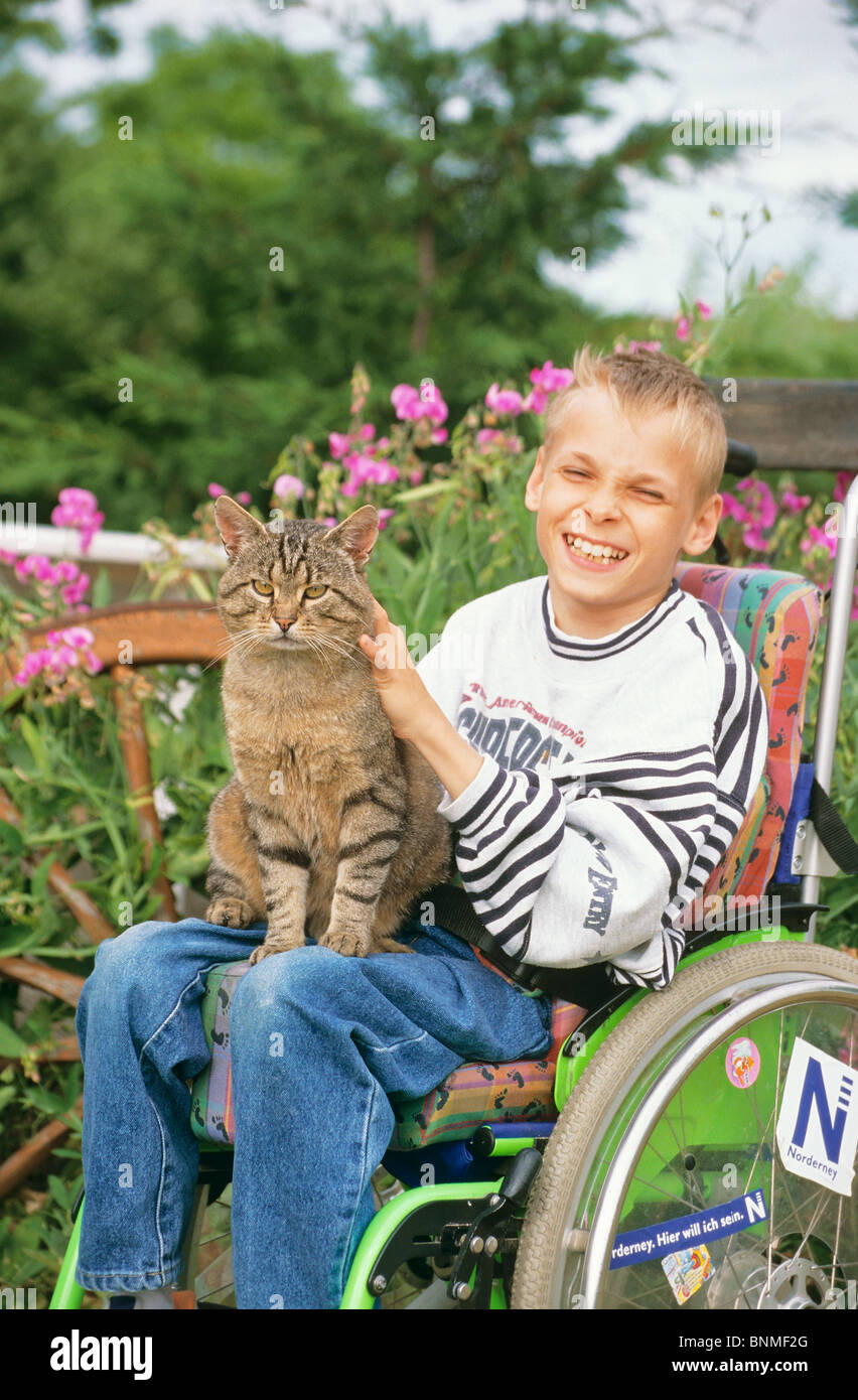 Disabled boy in wheelchair, stroking a cat Stock Photo
