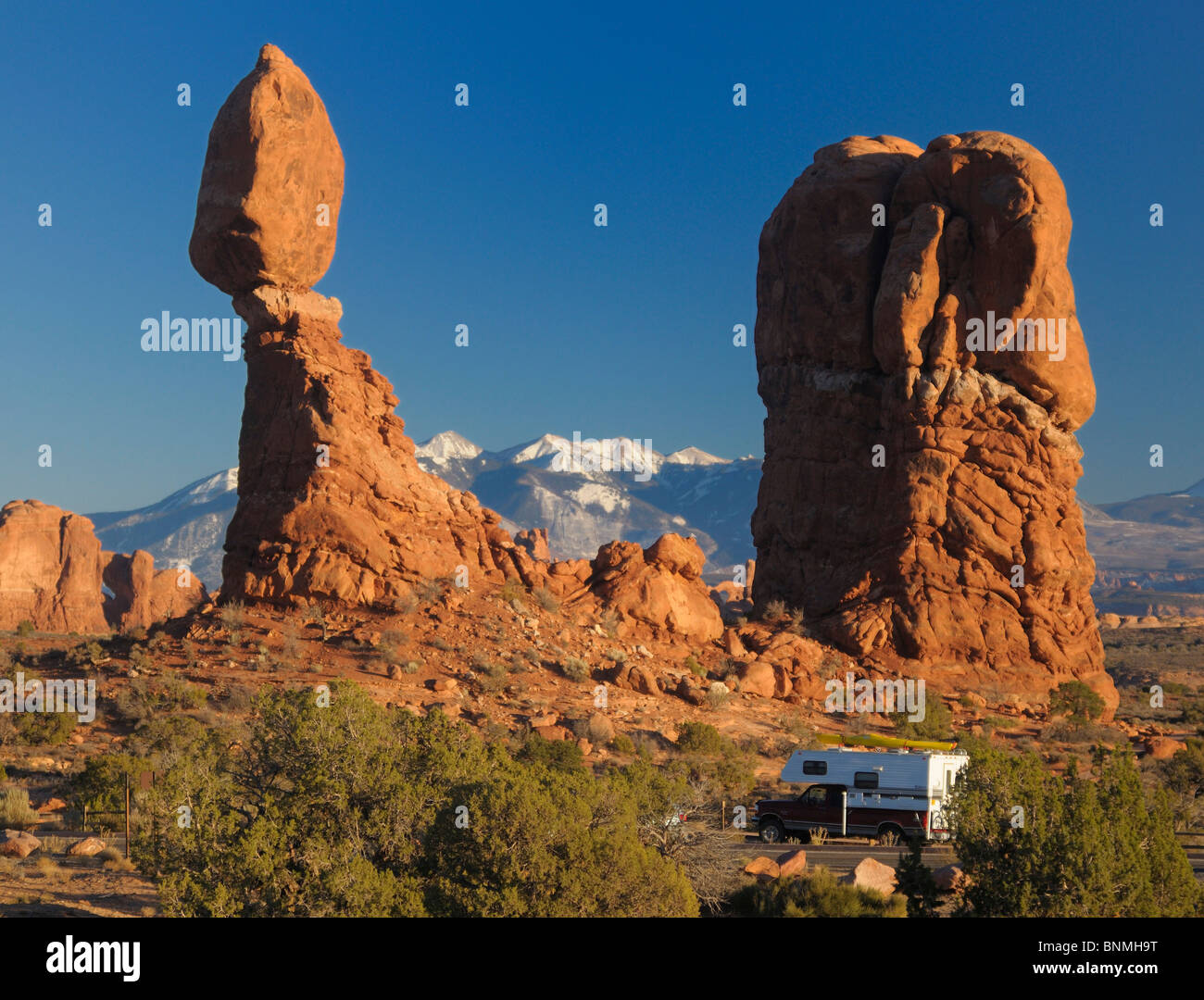 Balanced Rock rock stone formation camper camping caravan National Park landscape mountains snow nature sky sunlight Arches Stock Photo