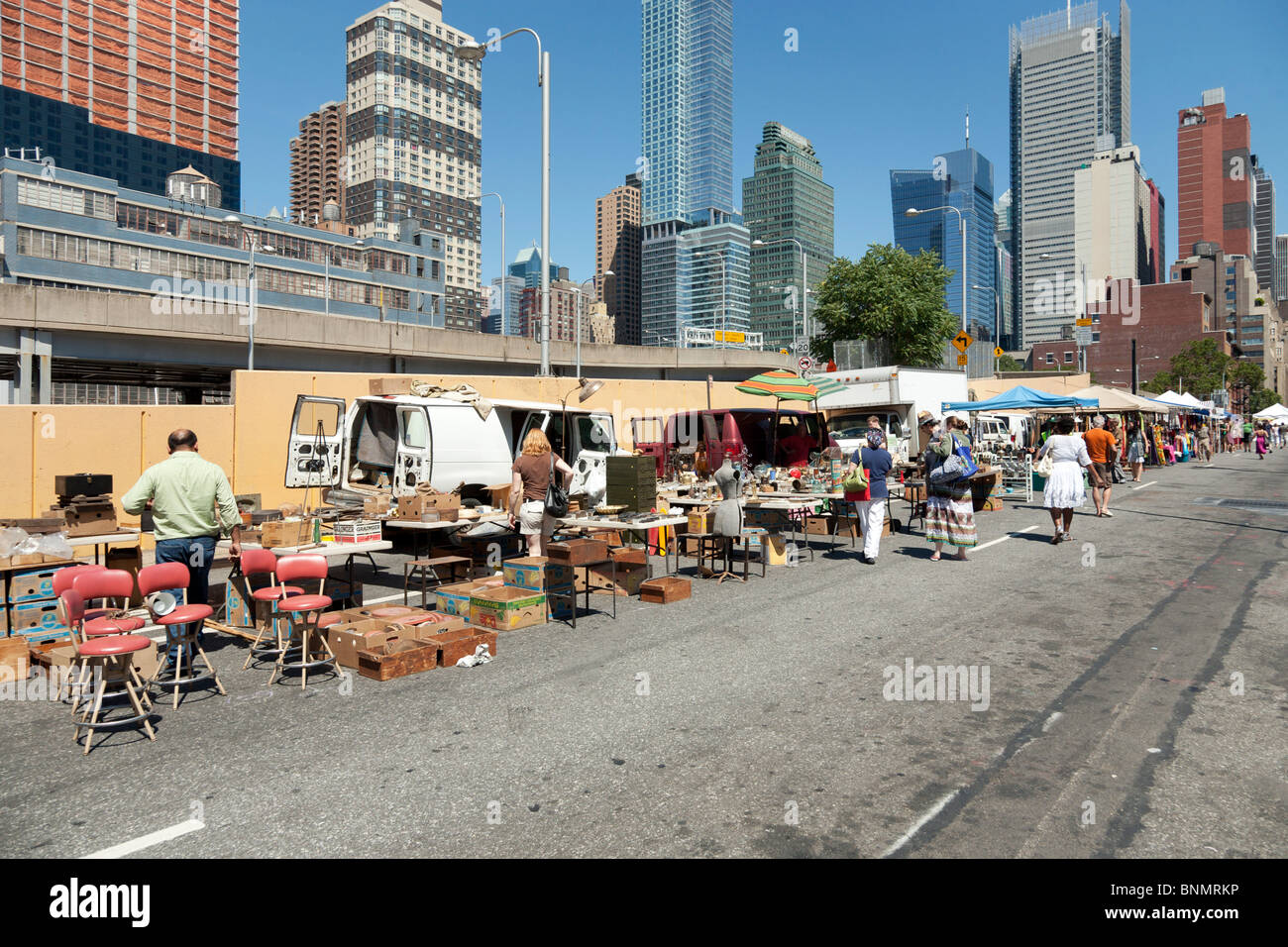 looking east along 39th street at colorful stalls & shoppers browsing variety at Hells Kitchen weekend flea market New York City Stock Photo