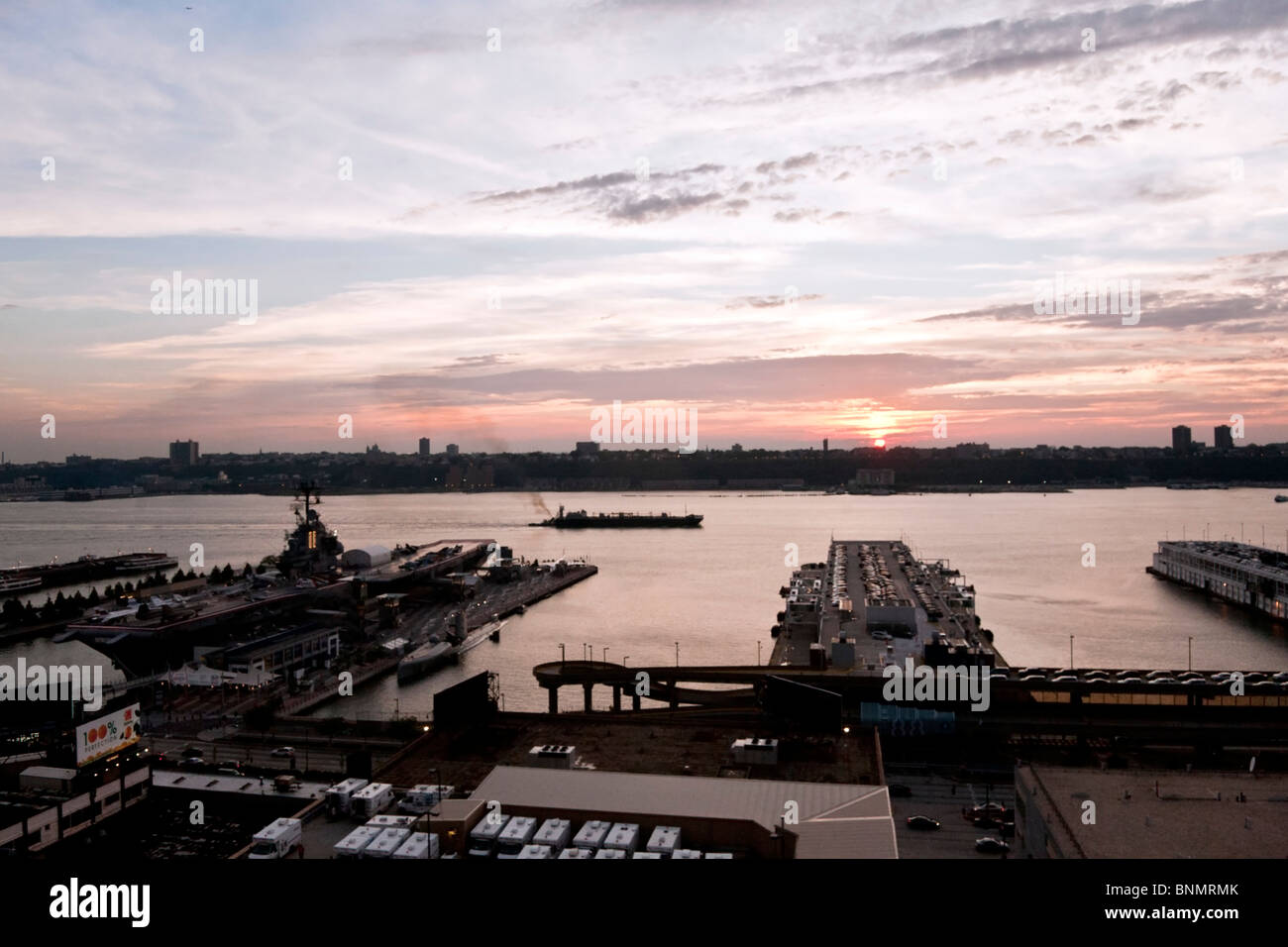 river view from West Side Manhattan of Intrepid & other piers, river traffic & sun setting over Jersey Palisades Stock Photo
