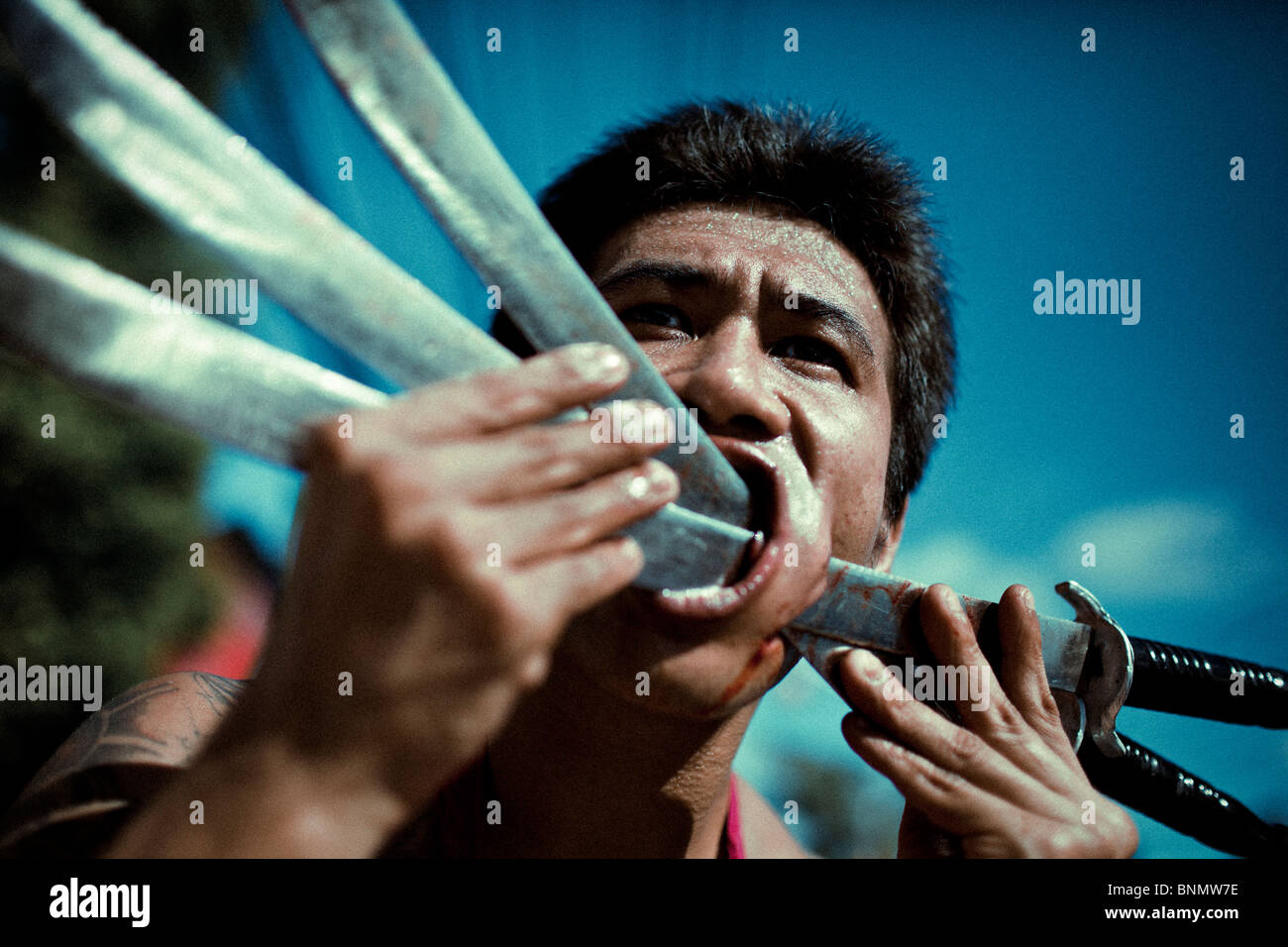Participant of the Vegetarian Festival with his cheek pierced with swords. Phuket. Thailand 2009 Stock Photo