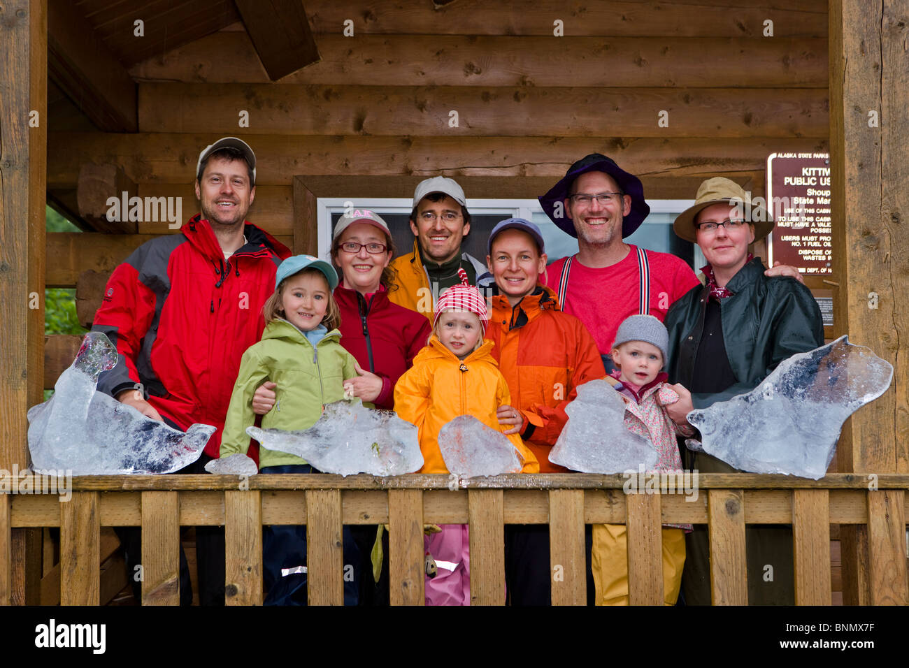 Group of family campers with toddlers standing on the porch of the