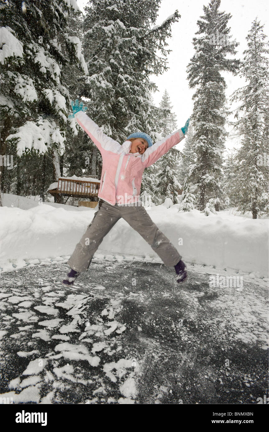 Young girl jumping on her snow covered trampoline in Girdwood, Alaska