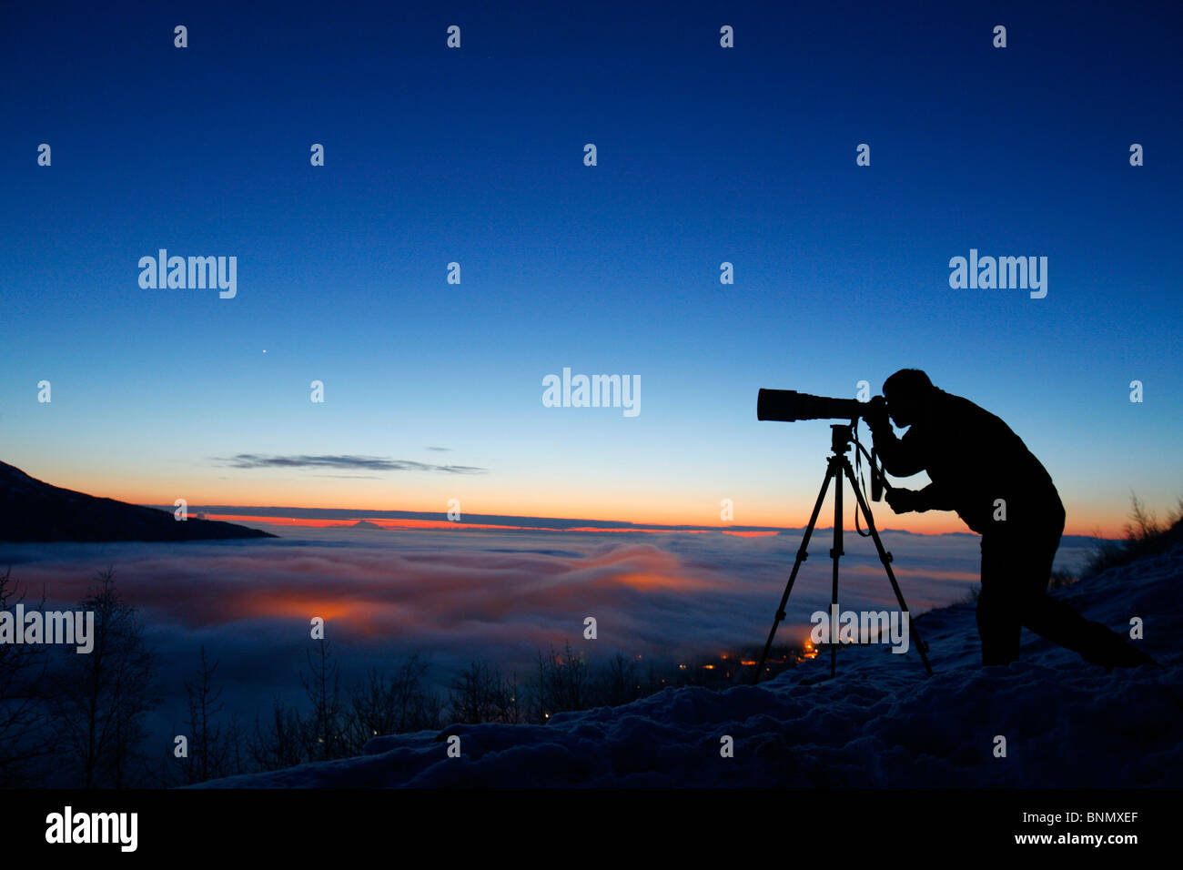 Silhouette of photographer at sunset in Eagle River Valley, Alaska, Winter Stock Photo