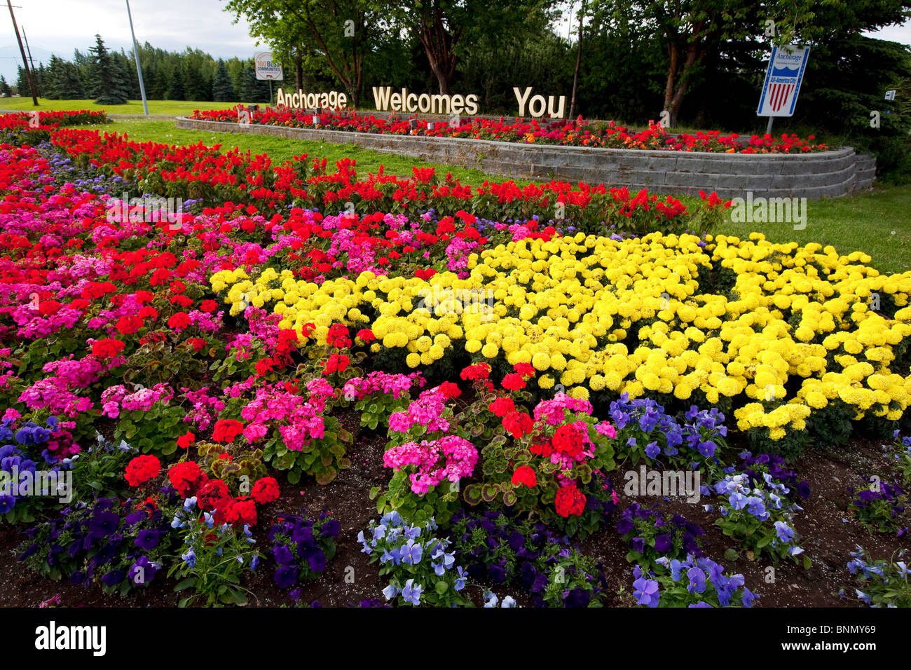 Colorful flower bed and an *Anchorage You* sign during Summer