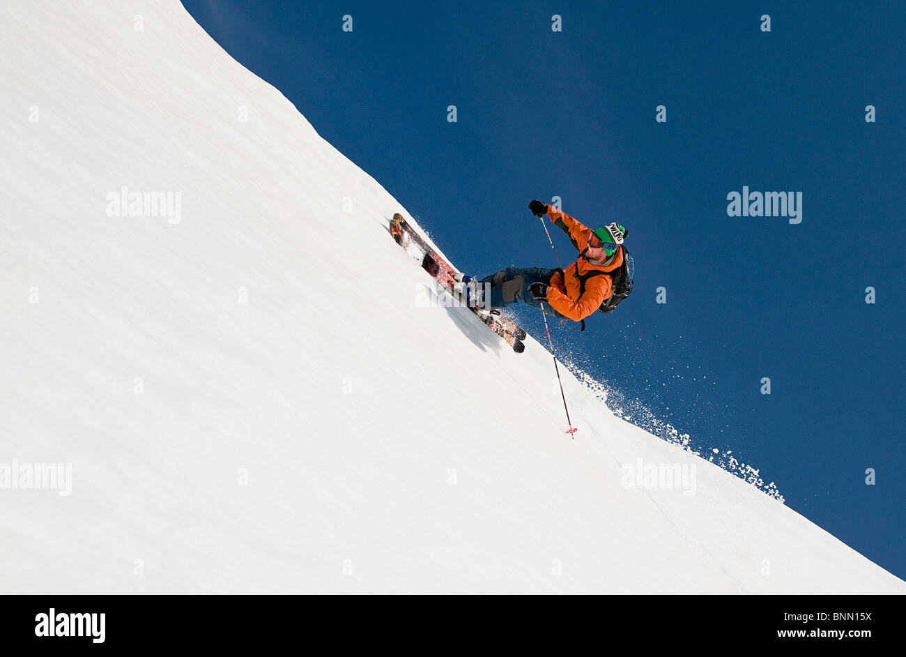 A skier rides the rim of a natural halfpipe while heliskiing near