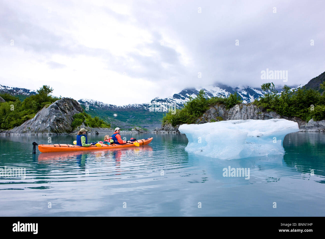 Family kayaking in Shoup Bay close to an iceberg from Shoup Glacier, Prince William Sound, Alaska Stock Photo