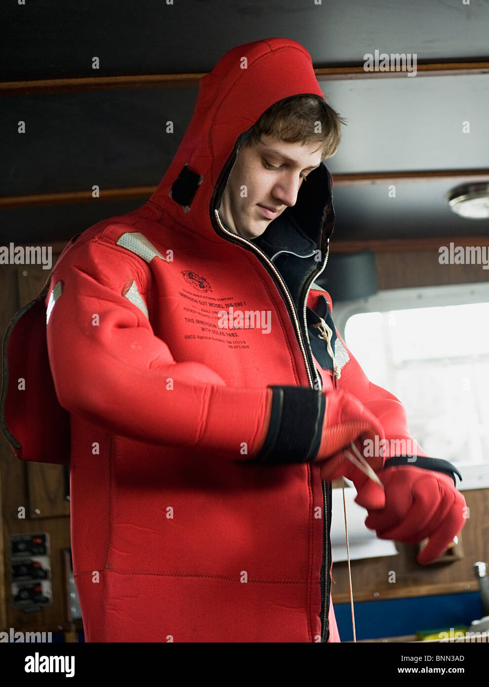 A crewmember on a commercial fishing vessel practices putting on his