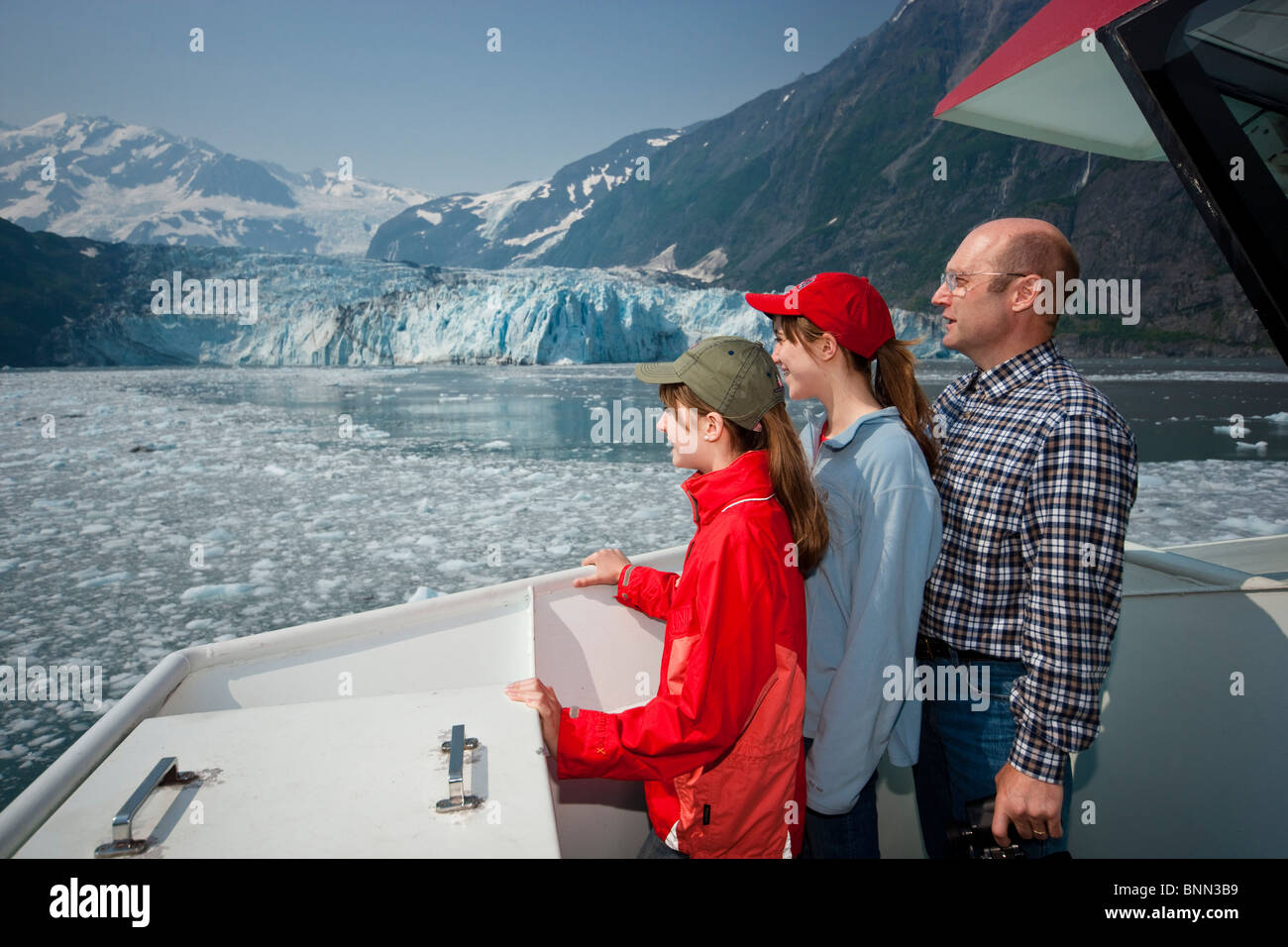 Father and two teenage daughters on a sightseeeing cruise in Prince Wiliam Sound near Harriman Glacier, Alaska Stock Photo