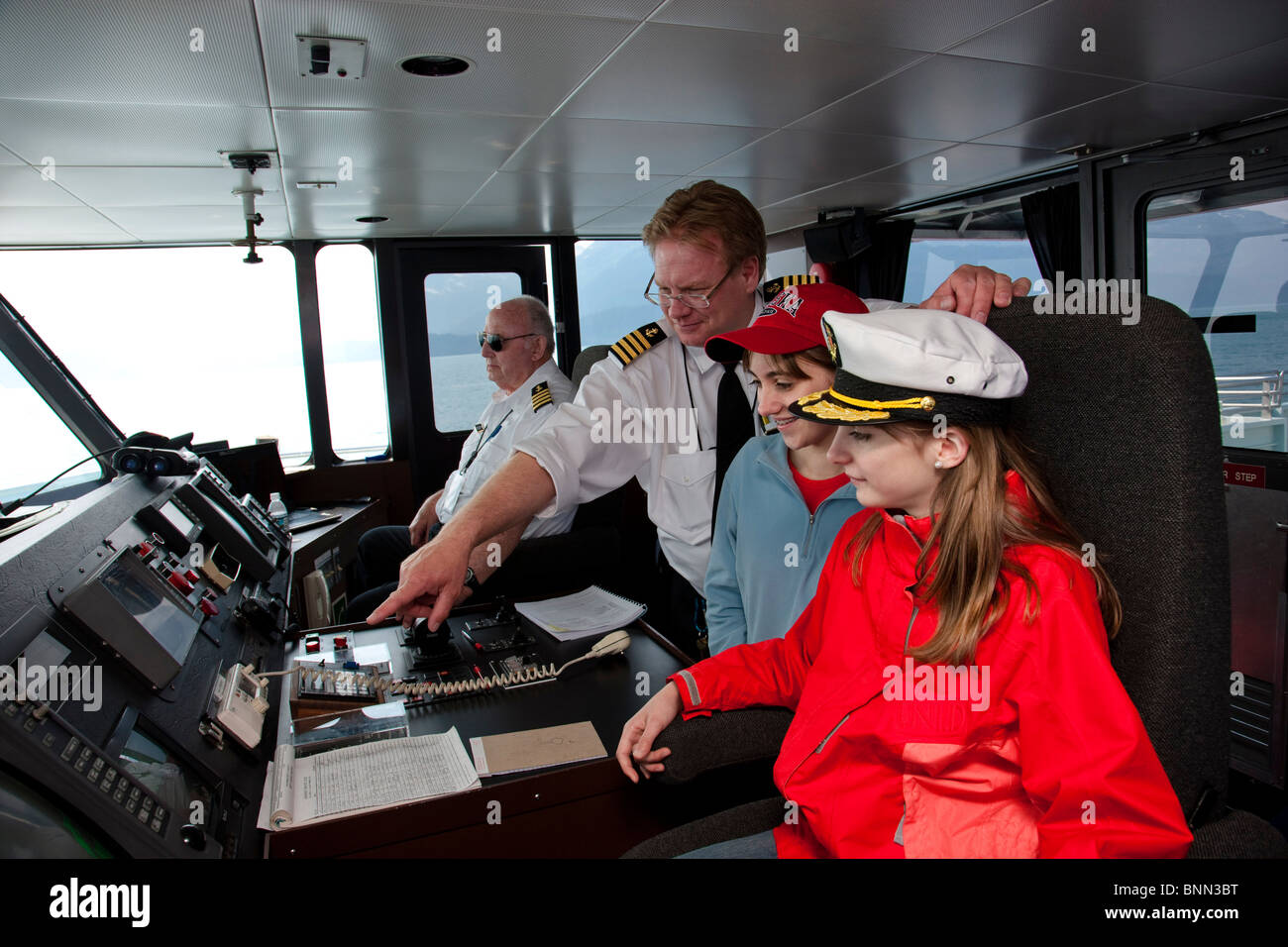 Two teenage girls visit the wheelhouse while on a sightseeeing cruise in Prince Wiliam Sound, Alaska Stock Photo