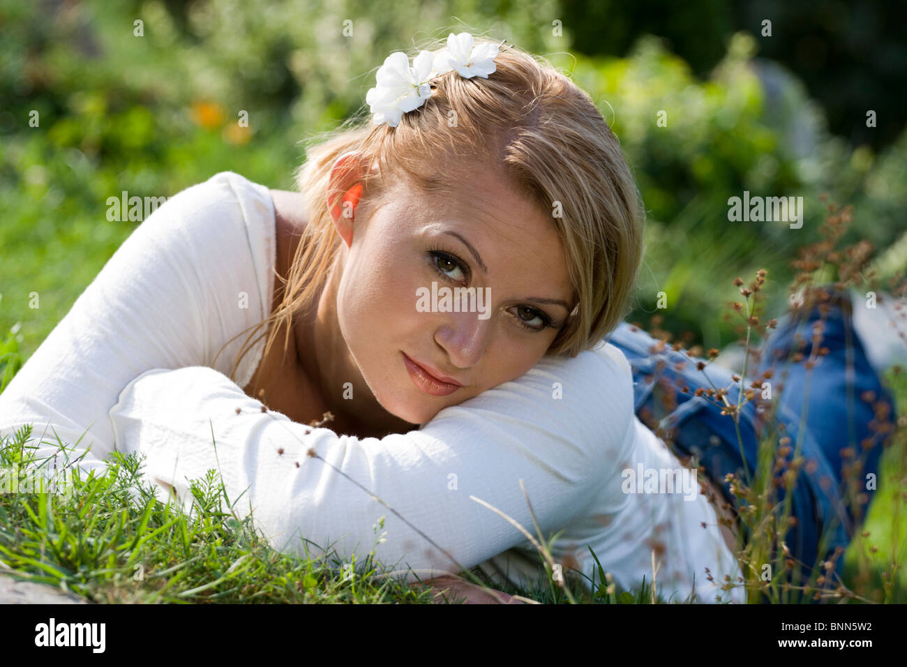 Young woman lying down in the summer grass. Stock Photo