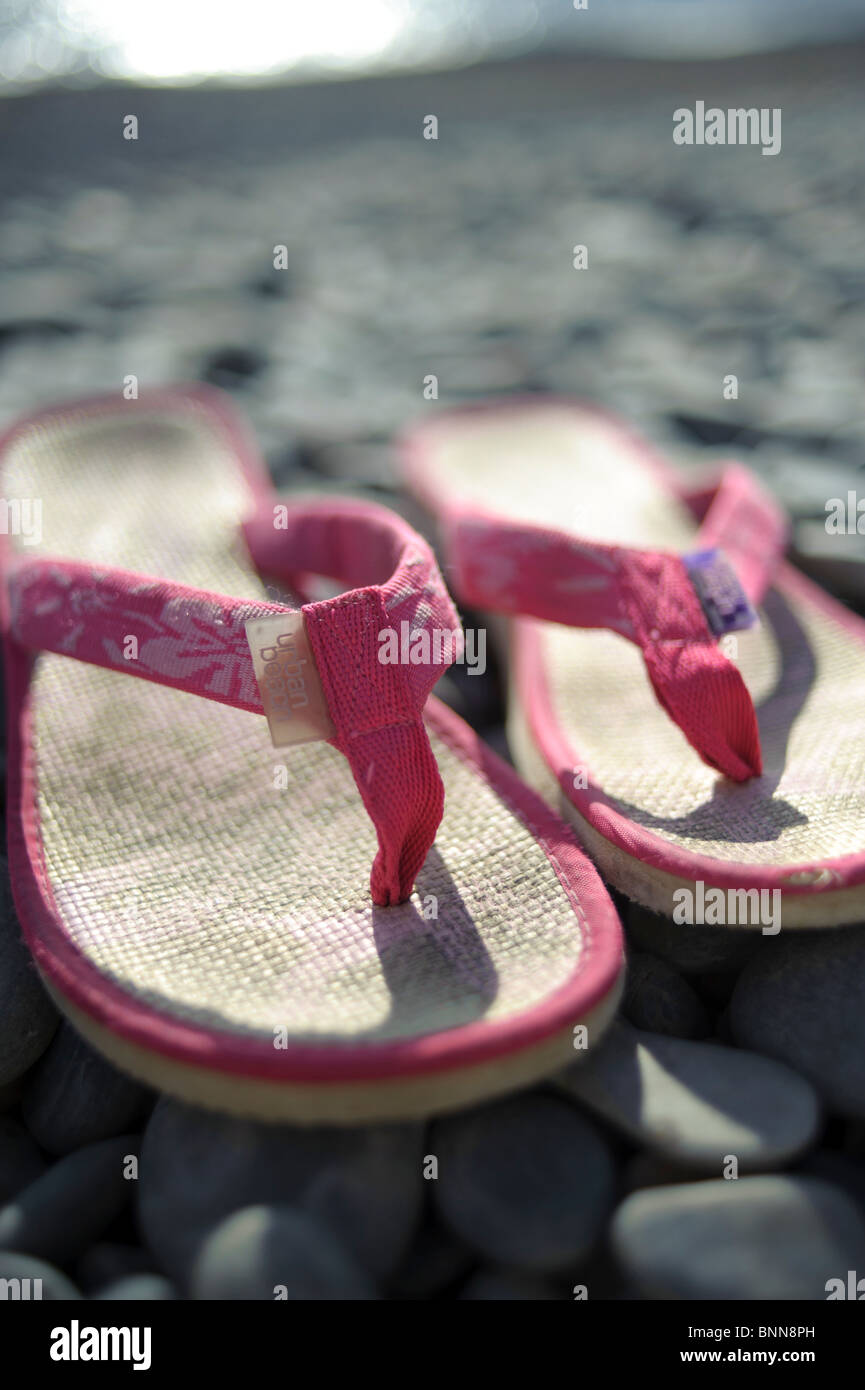 A pair of pink flip flops shoes on a pebble beach, summer UK Stock ...