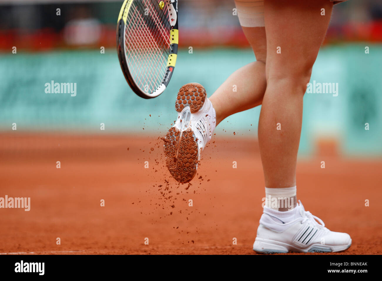 Tennis racket hitting sole of shoe to get rid of red clay Stock Photo
