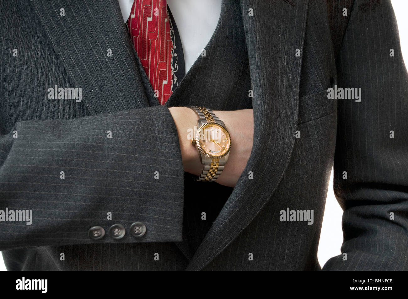 Upperclass man reaching in pocket for checkbook with gold watch Stock Photo