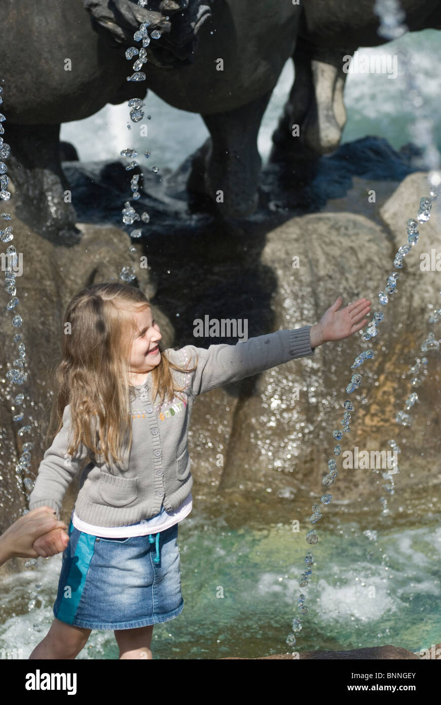 Little girl playing close to city fountain Stock Photo - Alamy