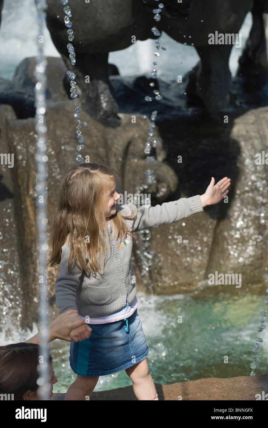 Little girl playing close to city fountain Stock Photo - Alamy