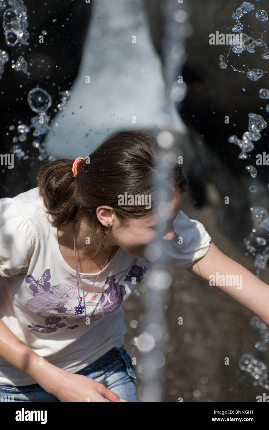 Young girl playing close to city fountain Stock Photo - Alamy