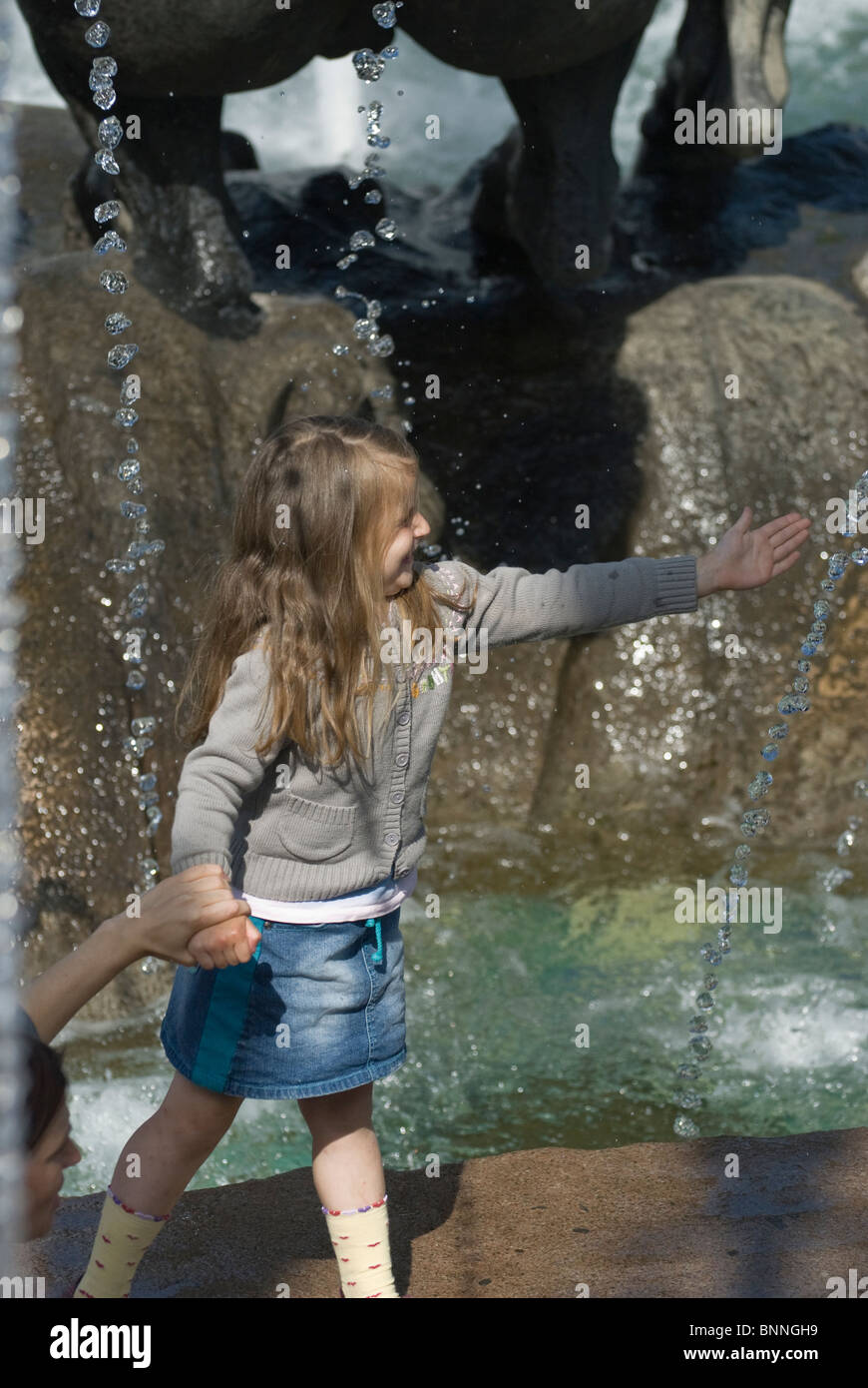 Little girl playing close to city fountain Stock Photo - Alamy