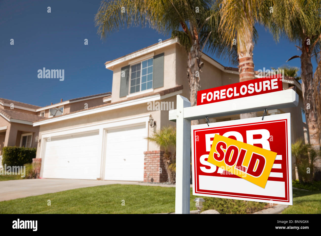 Red Foreclosure For Sale Real Estate Sign in Front of House. Stock Photo