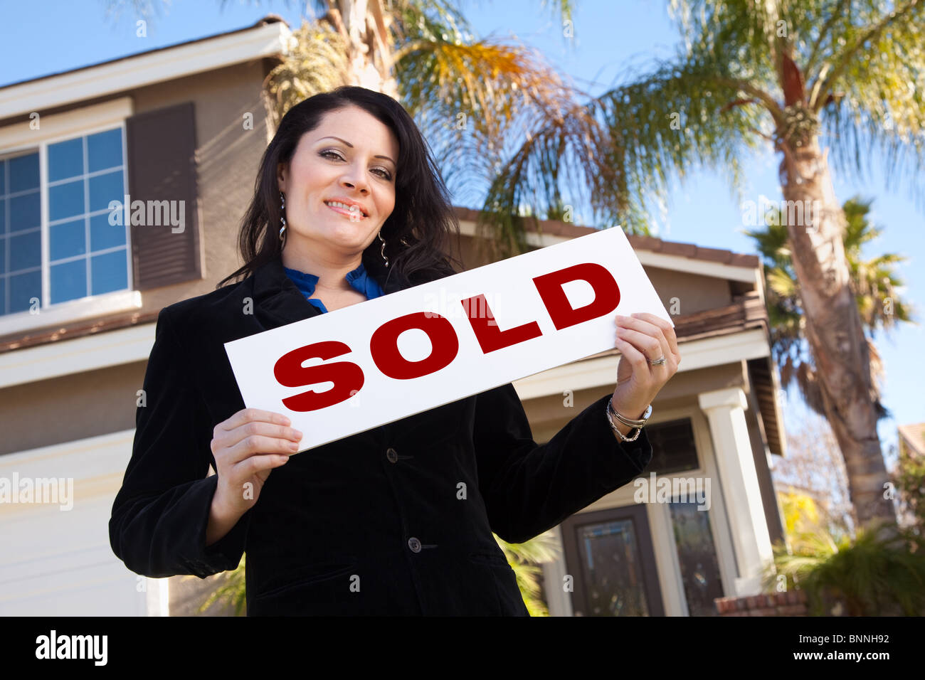 Happy Attractive Hispanic Woman Holding Sold Sign In Front of House ...