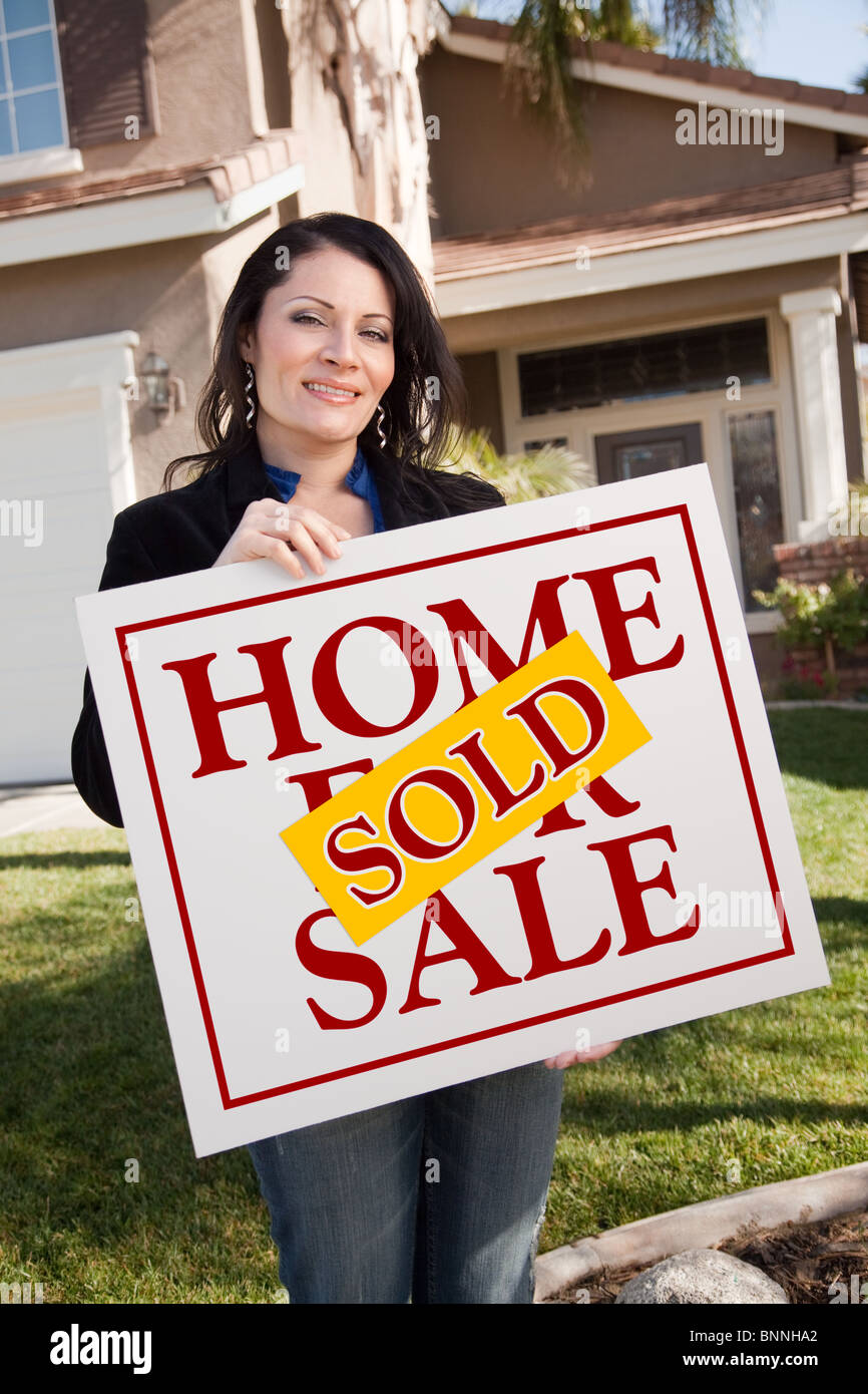 Happy Attractive Hispanic Woman Holding Sold Home For Sale Sign In ...