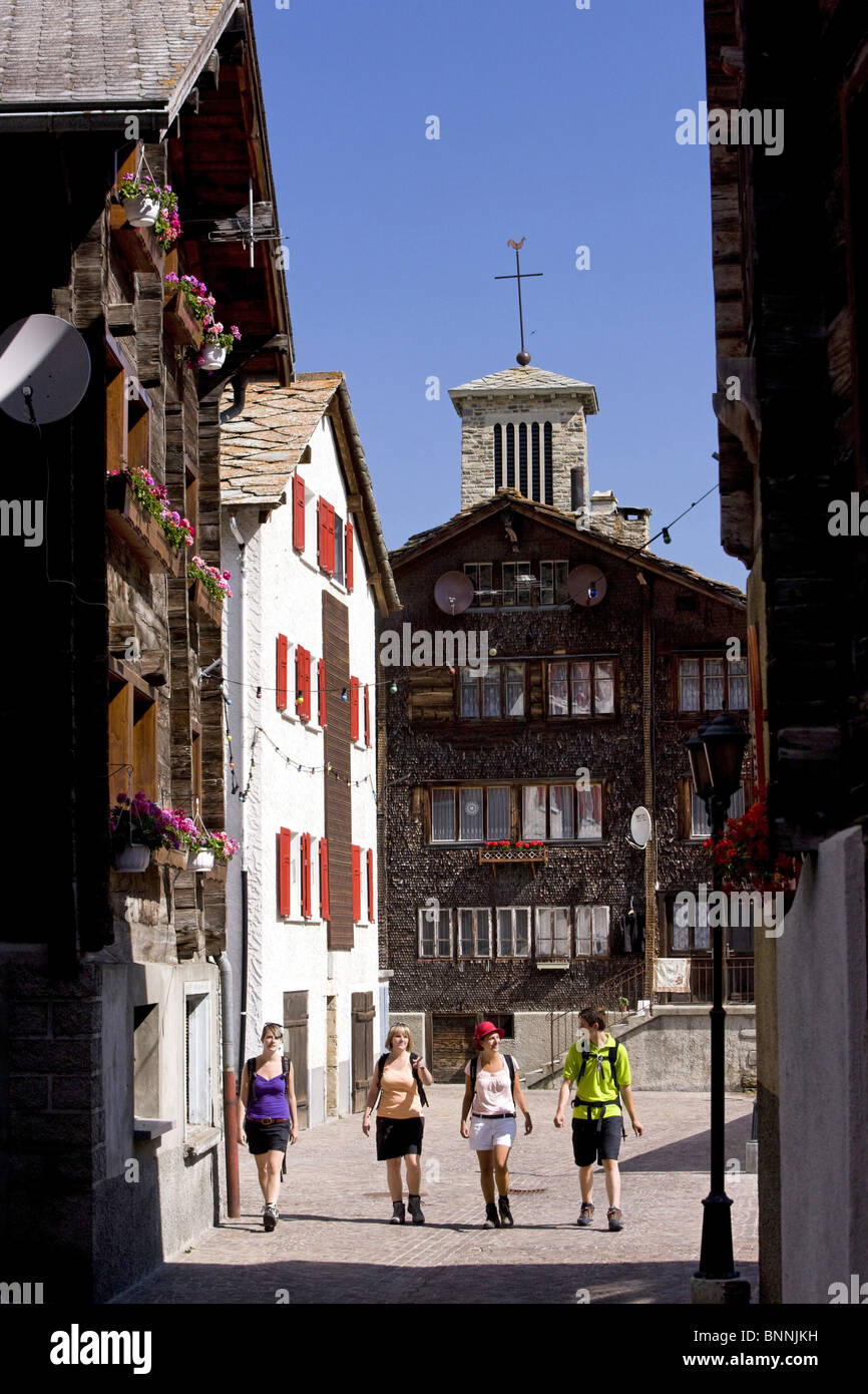 Switzerland swiss Saas Grund place houses homes buildings constructions walking hiking group four persons valley of Saas Stock Photo