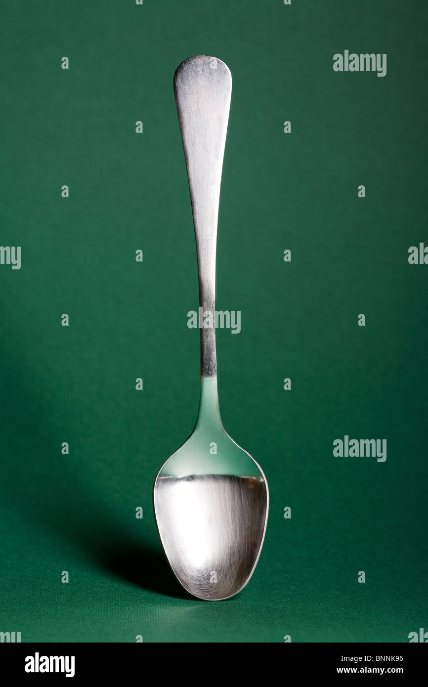 metal spoon isolated on green background Stock Photo