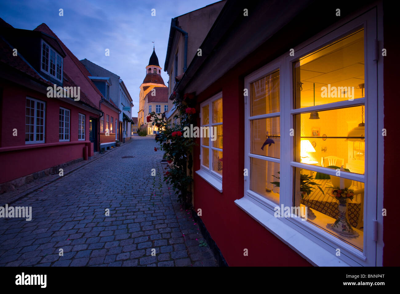 Faaborg Denmark Funen Fyn town city Old Town street cobblestone houses homes church lighting dusk twilight flowers roses windows Stock Photo