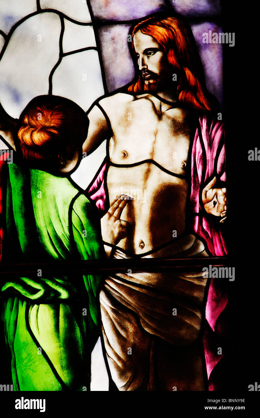 Stained glass window depicting Jesus and Thomas (Doubting Thomas) the Apostle touching his wound. Stock Photo