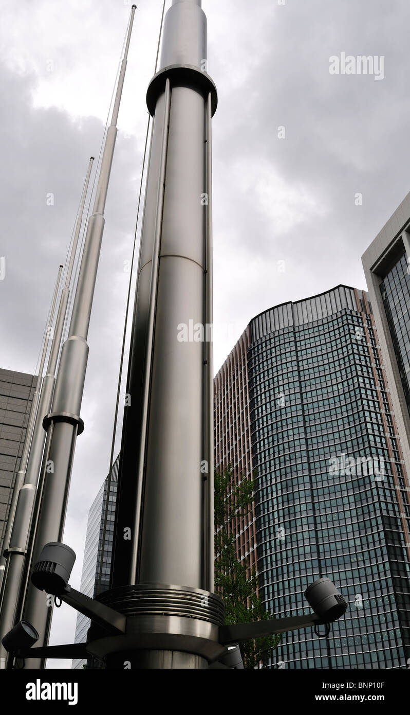 Shiny flag poles with high rise buildings in the background against overcast sky (Tokyo, Japan) Stock Photo