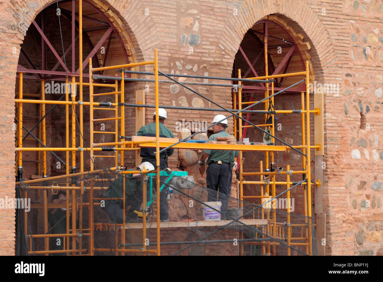 Workers on scaffolding carring out restoration in a wall of the Alcazaba in the Alhambra palace in Granada Stock Photo
