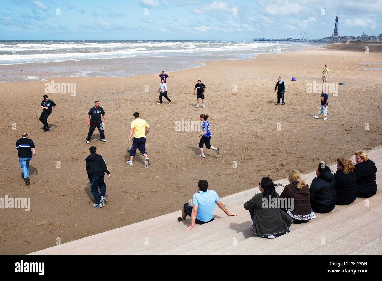 A group of people plays a football match on the beach in Blackpool, England. Stock Photo
