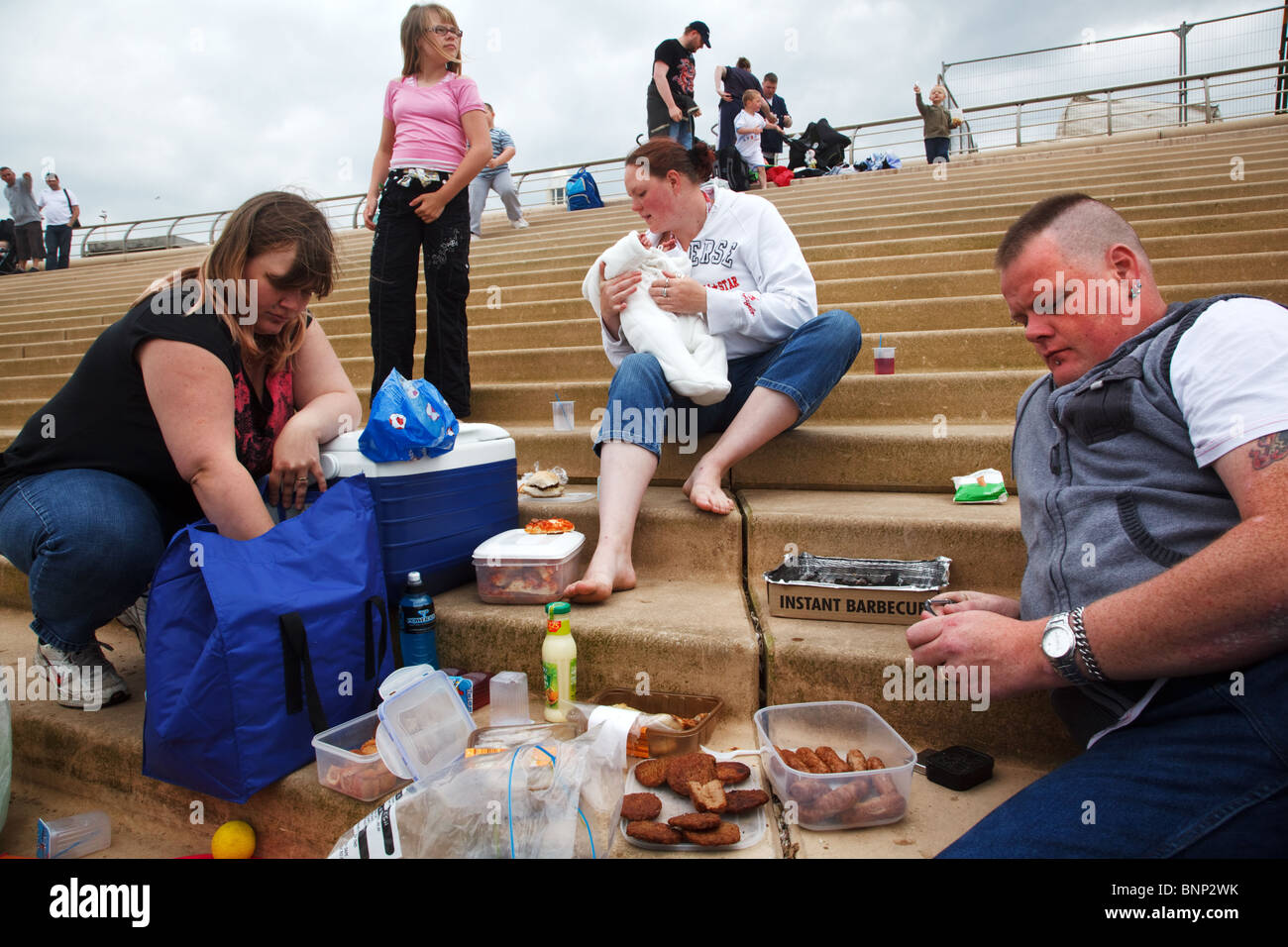 A family having meal on the steps by the beach in Blackpool, England. Stock Photo