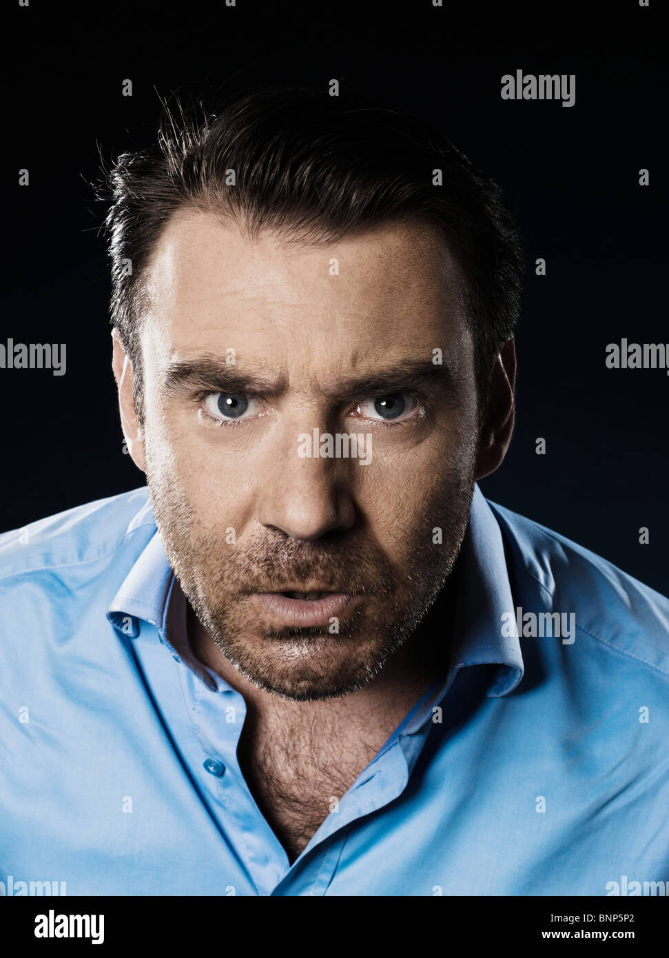 one caucasian man unshaven angry portrait looking at camera isolated studio on black background Stock Photo