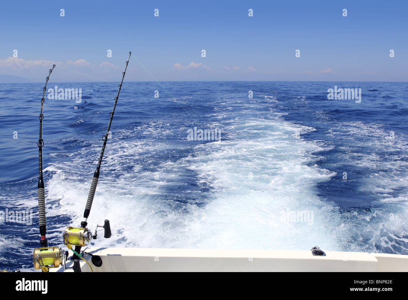 blue sea fishing sunny day trolling rod reels wake ocean big game Stock Photo