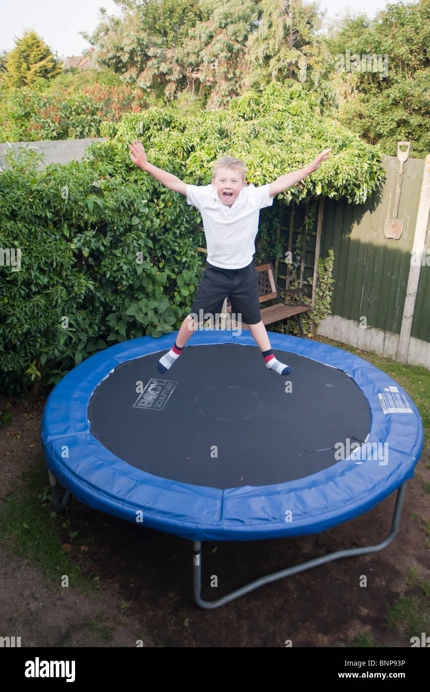 A MODEL RELEASED six year old boy jumping on a trampoline showing movement in the Uk Stock Photo