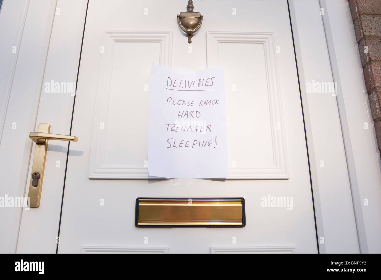 A front door with sign left for couriers and deliveries saying please knock hard teenager sleeping in the Uk Stock Photo