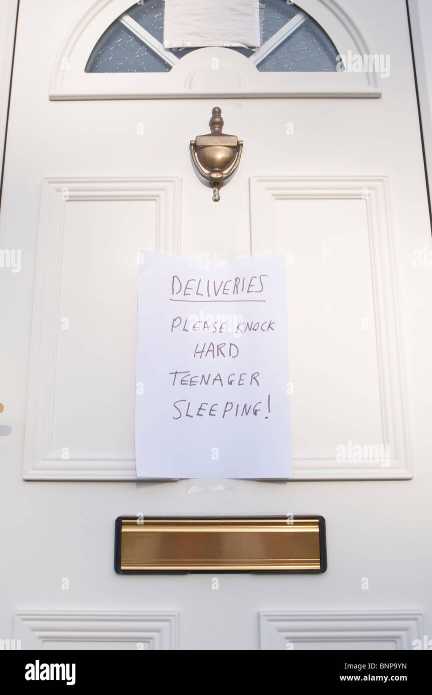 A front door with sign left for couriers and deliveries saying please knock hard teenager sleeping in the Uk Stock Photo