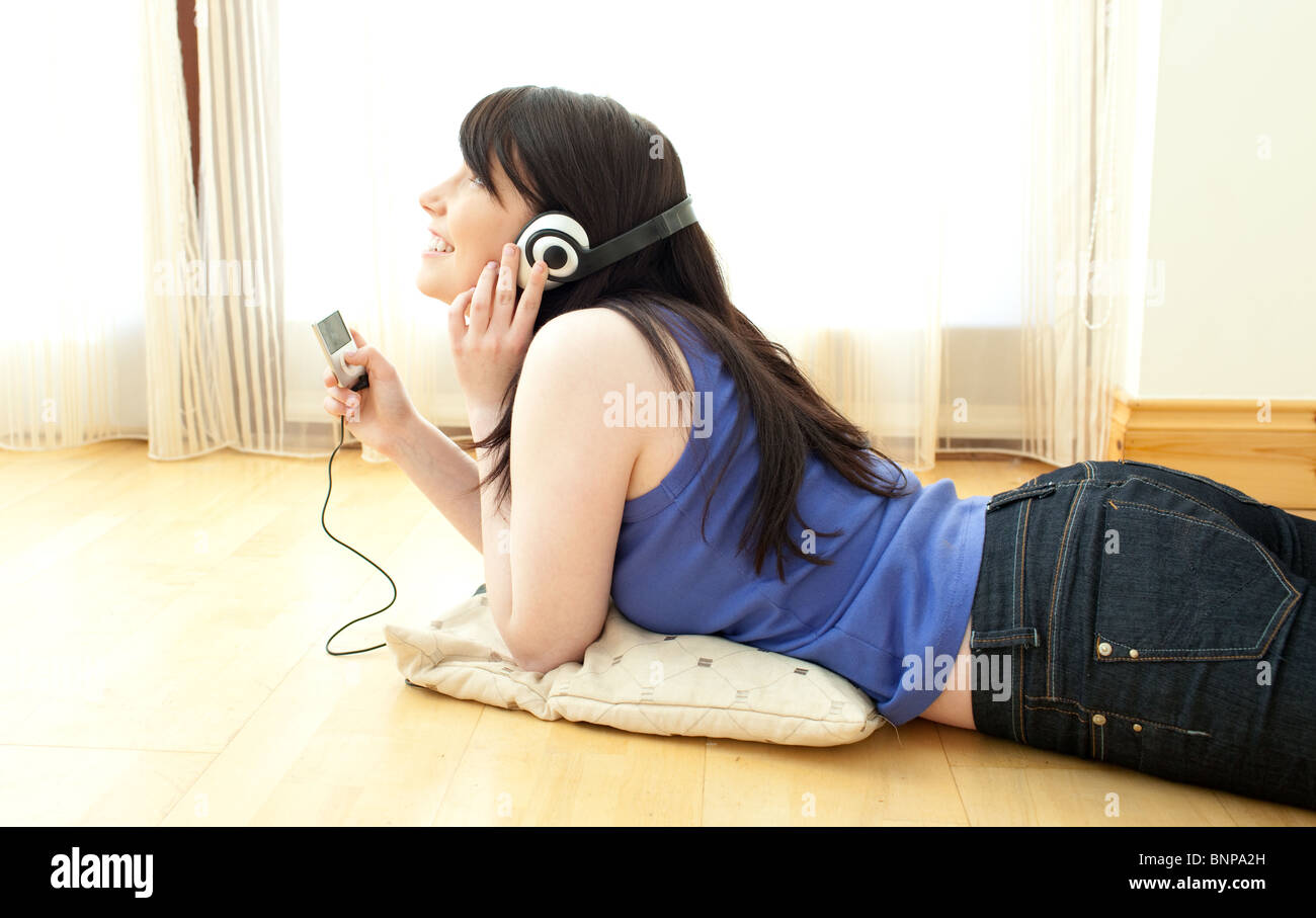 Happy woman listening music lying on the floor Stock Photo - Alamy