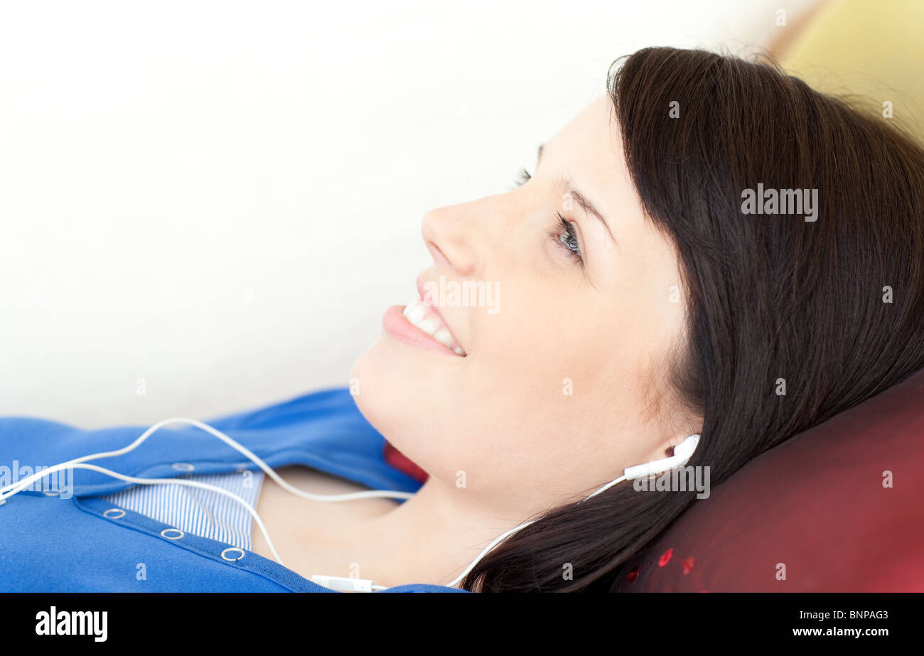 Smiling teen girl listening music lying on a sofa Stock Photo