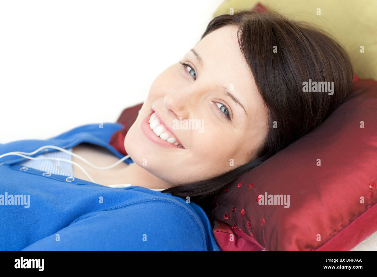 Cheerful young woman listening music lying on a sofa Stock Photo - Alamy