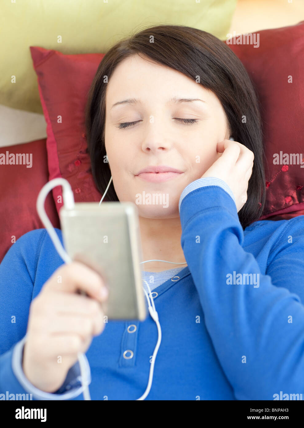 Brunette young woman listening music lying on a sofa Stock Photo - Alamy