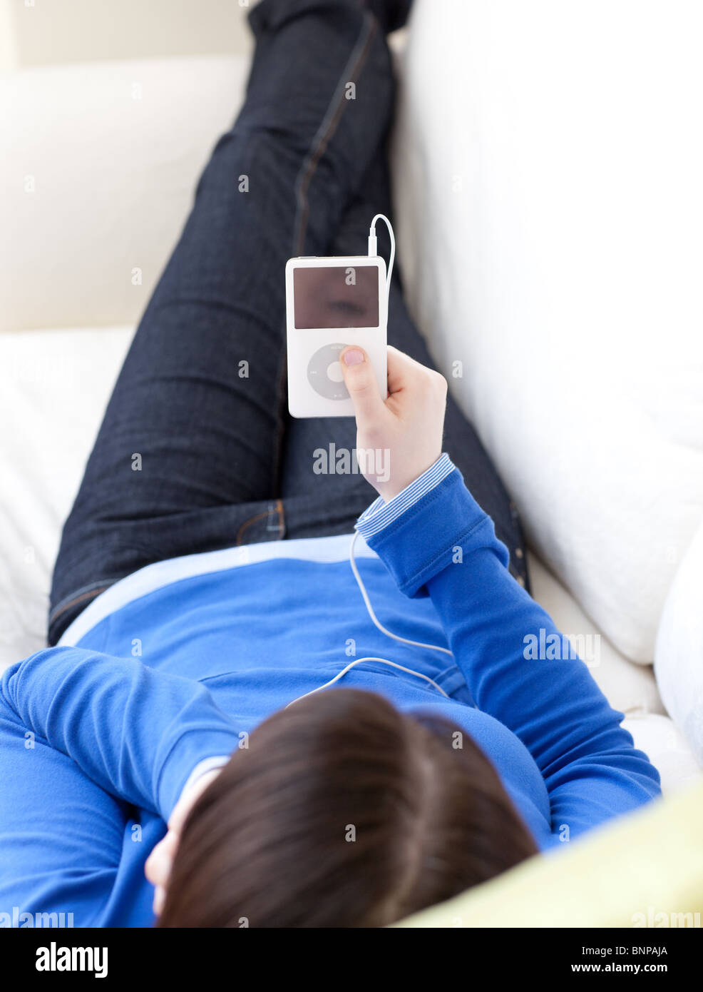 Close-up of a teen girl listening music lying on a sofa Stock Photo