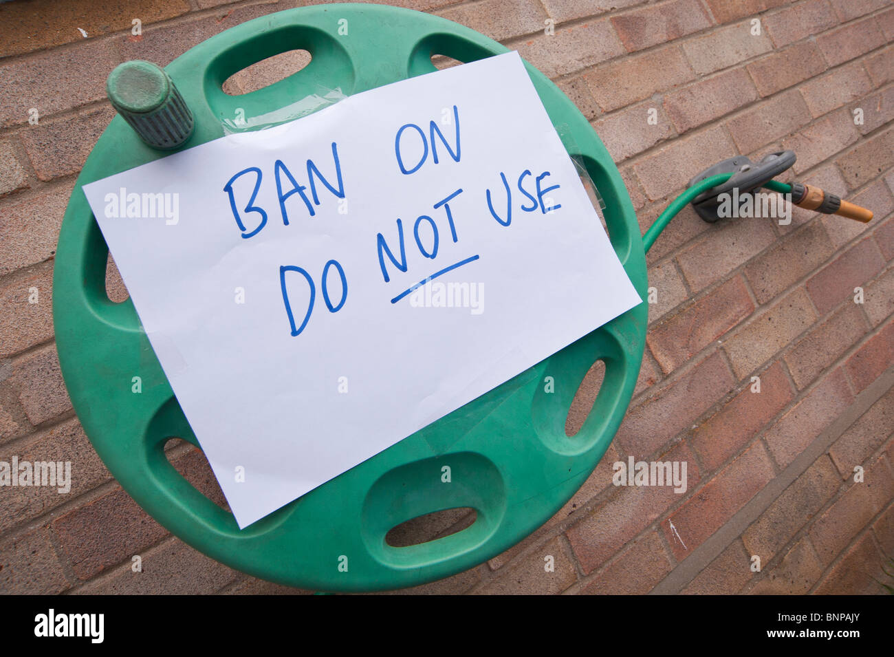 A hose pipe with a sign on it stopping use due to a hose pipe ban in the Uk Stock Photo