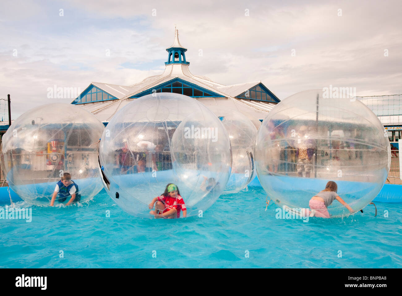 Children playing in water walkers on Llandudno pier, North Wales Stock