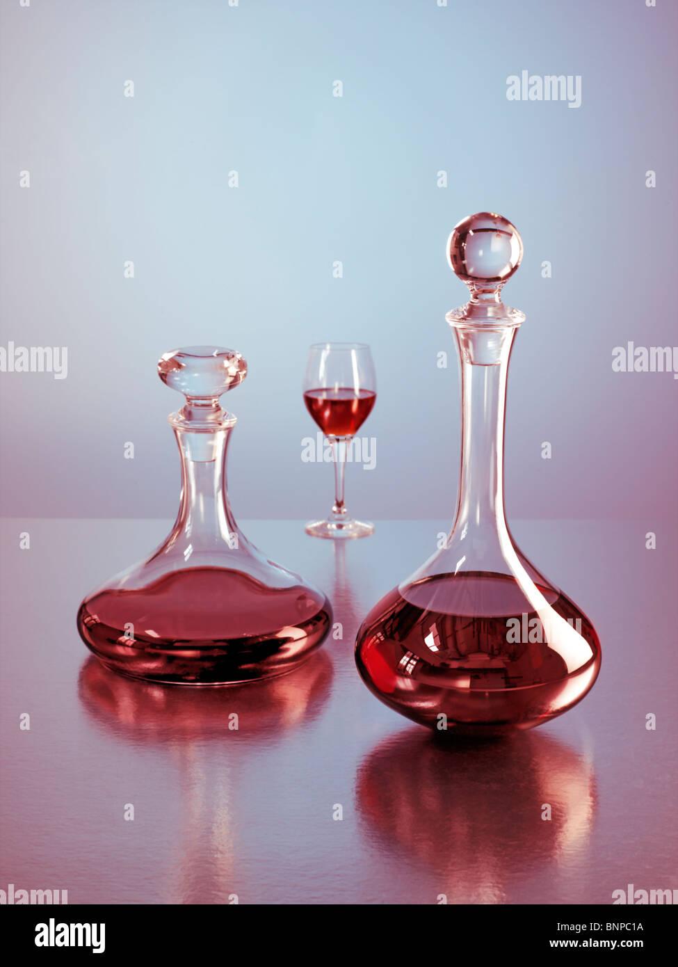 Two decanters with red wine and glass in background Stock Photo