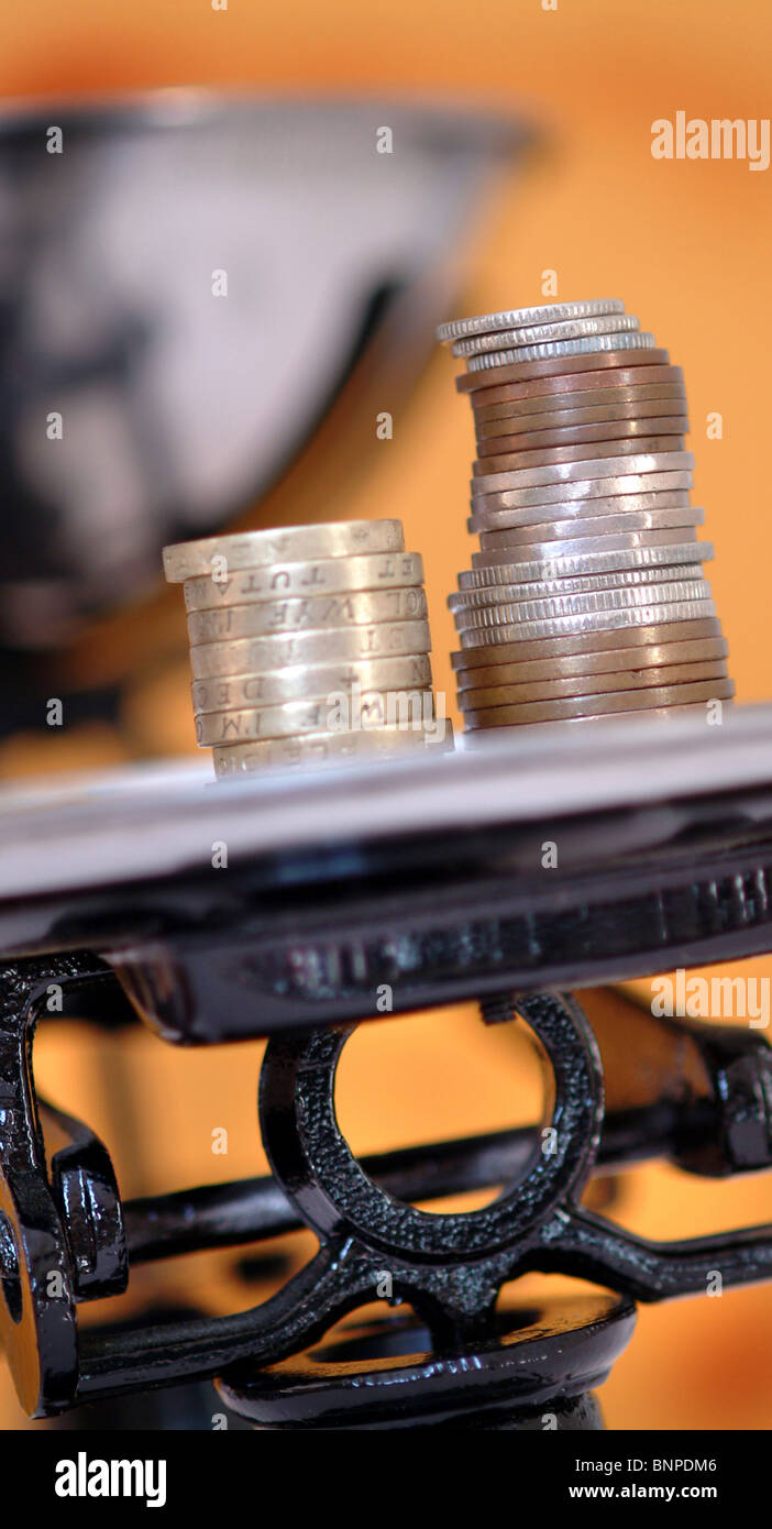 Coins weigh down a set of scales UK Stock Photo Alamy